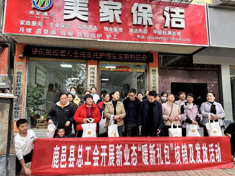 鹿邑县总工会在鹿邑美家保洁门店前开展新业态'暖新礼包'核销及发放活动,家政员领取工会福利。
