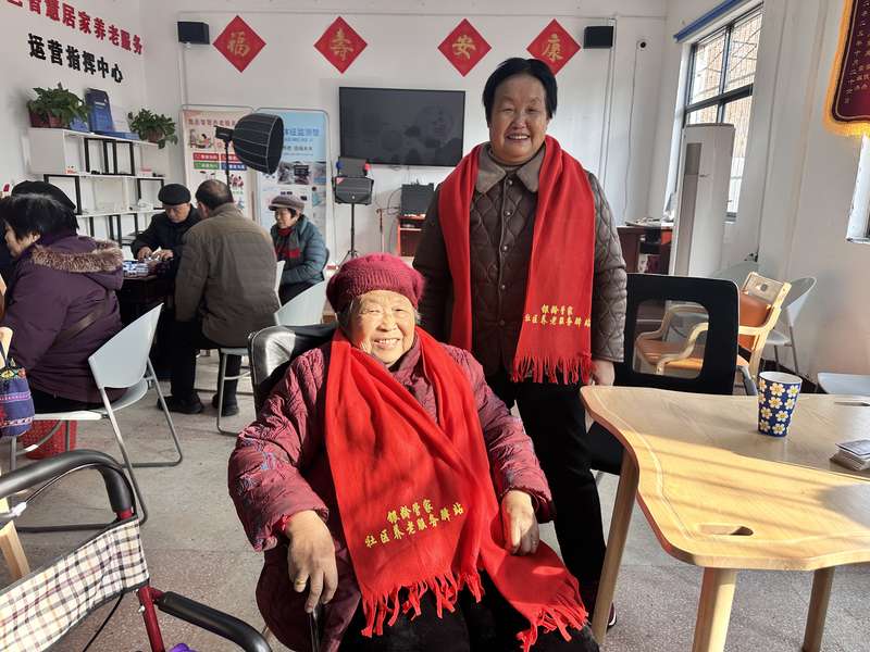 鹿邑智慧居家养老服务运营指挥中心内,老人佩戴'银龄管家社区养老服务驿站'红围巾合影。